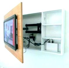 a television mounted to the side of a white wall next to a shelf with wires