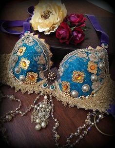 two blue and gold bras on a wooden table with flowers in the back ground