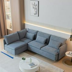 a living room with a sectional couch and coffee table in the corner, next to a large window