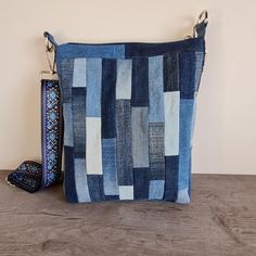 a blue patchwork purse sitting on top of a wooden table next to a wallet