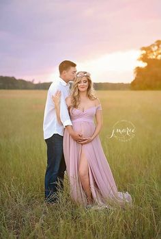 a pregnant couple standing in the grass at sunset