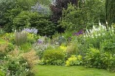 the garden is full of different types of flowers and plants, including grasses, shrubs, and trees