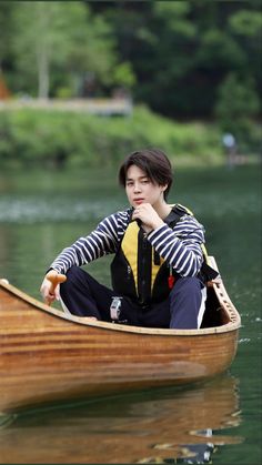 a woman sitting in a small boat on the water with her hand under her chin