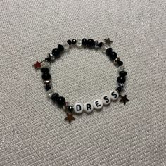 a beaded bracelet with the word dress written in white letters and stars on it