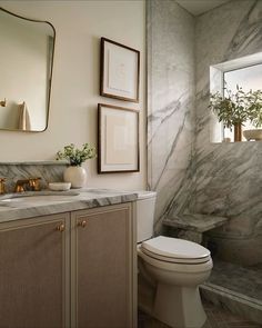 a white toilet sitting next to a bath tub under a window in a bathroom with marble walls