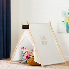 a teepee tent sitting on top of a wooden floor next to a blue curtain