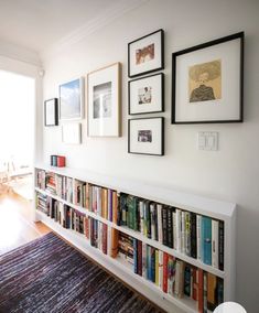 a bookshelf filled with lots of books on top of a wooden floor next to a window