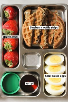 a lunch box with eggs, strawberries and waffles