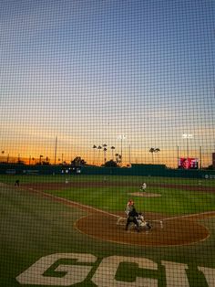 a baseball game in progress with the sun setting