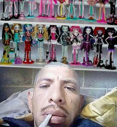 a man with his tongue out in front of a shelf full of barbie dolls