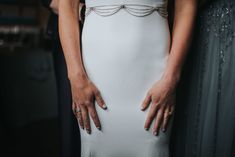 two people standing next to each other with their hands on the back of their dresses