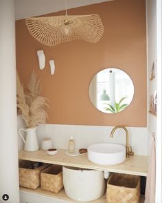 a bathroom with an orange wall and white counter top, two baskets under the sink