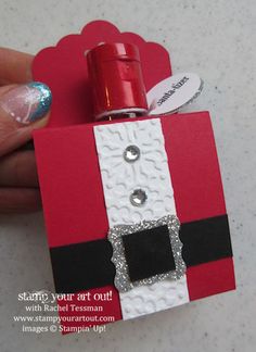 a hand holding a small red and white box