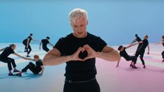 a man standing in front of a group of people making a heart shape with his hands