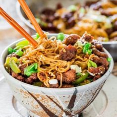 a bowl filled with noodles and meat on top of a plate next to another bowl