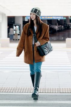 a woman is walking down the street with her hand in her pocket and wearing a hat