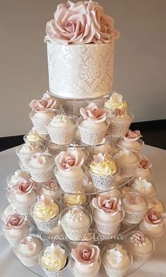 a white wedding cake with cupcakes in the shape of a flower on top