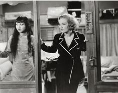 an old photo of two women standing in front of a mirror looking at each other