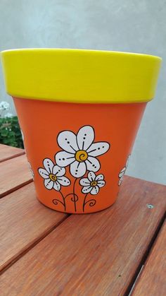 an orange flower pot sitting on top of a wooden table