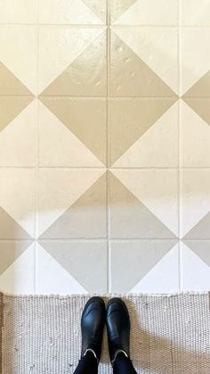 a pair of black shoes sitting on top of a white floor next to a tiled wall