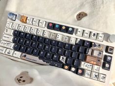 a computer keyboard sitting on top of a white blanket next to a buttonhole hole