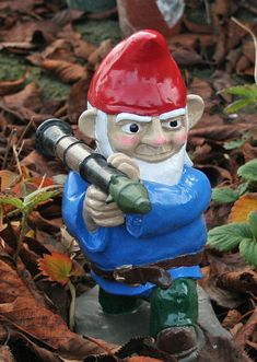 a gnome figurine holding a baseball bat on top of some leaves and grass