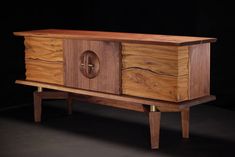 a wooden cabinet sitting on top of a black floor next to a table with two legs