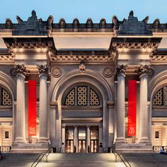 an ornate building with red pillars and columns on the front entrance to it at night