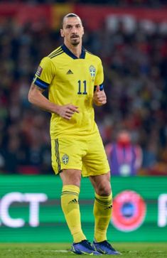 a soccer player is running on the field with his hand in his pocket and looking at the camera