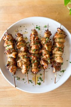 chicken skewers on a white plate with parsley