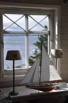 a sailboat sitting on top of a white table next to a lamp and window