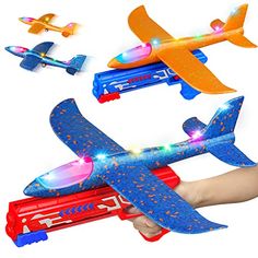 a hand holding a toy airplane with lights on it's wings and other toys flying around