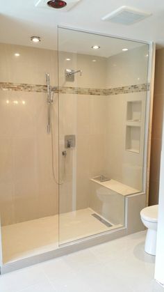 a bathroom with a walk in shower next to a white toilet and stand up shower