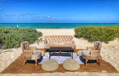 a living room filled with furniture on top of a sandy beach next to the ocean