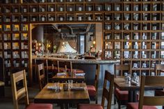 an empty restaurant with many tables and chairs in front of bookshelves filled with bottles