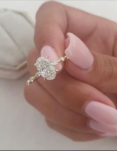 a woman's hand holding a pink manicure with a diamond ring on it