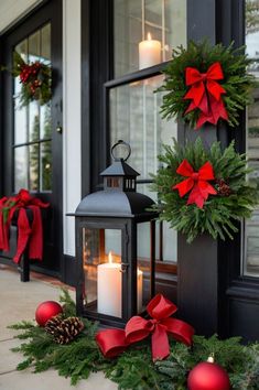 a lantern and christmas wreath on the front porch with red balls, pine cones and candles