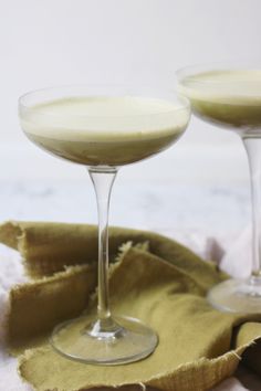 two glasses filled with liquid sitting on top of a table next to a cloth and napkin