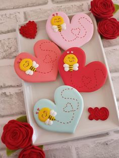 three heart shaped cookies sitting on top of a white plate next to flowers and roses