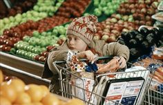 a young boy pushing a shopping cart in a grocery store