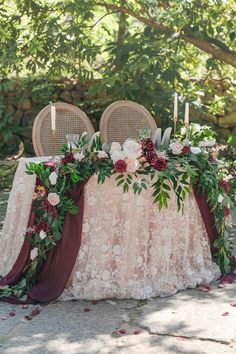 the table is set with two chairs and flowers on it, while candles are lit