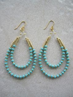 two pairs of turquoise beaded hoop earrings on a white surface with gold earwires