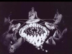 people sitting around a table with candles in the shape of a heart