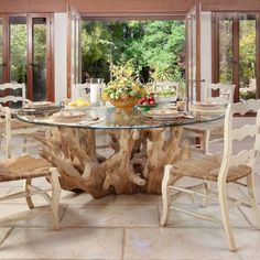 a glass table with chairs around it in front of large windows that look out onto the outdoors