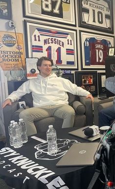 two men sitting on couches in a room with football memorabilia and posters behind them