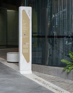 a sign on the sidewalk in front of a building that has glass doors and windows