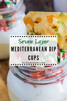 a jar filled with mexican dips next to a spoon full of dips and the title overlay reads seven layer mediterranean dip cups