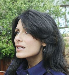 a woman with long black hair wearing a blue coat