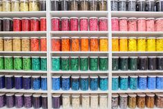 the shelves are filled with many different colored sprinkles and jars on them