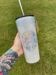 a person holding up a starbucks cup with a unicorn sticker on it's side